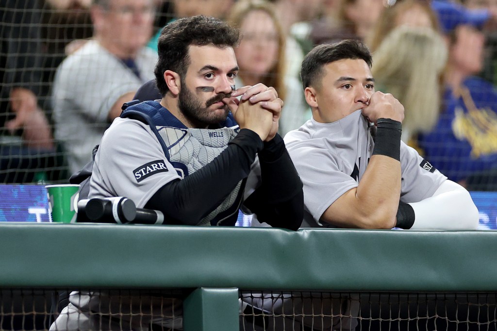 Austin Wells and Anthony Volpe of the New York Yankees reacting as teammate Oswaldo Cabrera is taken away in an ambulance during a game against the Seattle Mariners