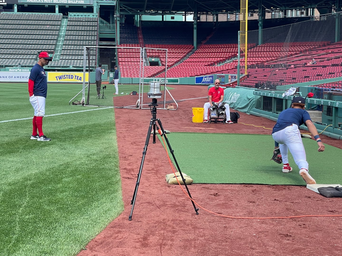 Red Sox manager Alex Cora (left) watches Kristian Campbell take some grounders from infield coach José Flores (seated) to see how the rookie handled playing first base before Friday's game against the Braves at Fenway Park.