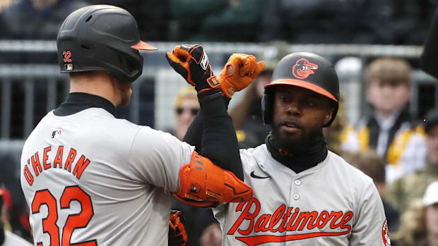 Cedric Mullins and Ryan O'Hearn bumping fists with each other in gray uniforms and black hats.