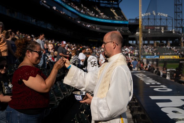 People participate in Holy Communion at the end of a Catholic Mass while celebrating the election of Pope Leo XIV with a citywide gathering at Rate Field on June 14, 2025. (Audrey Richardson/Chicago Tribune)