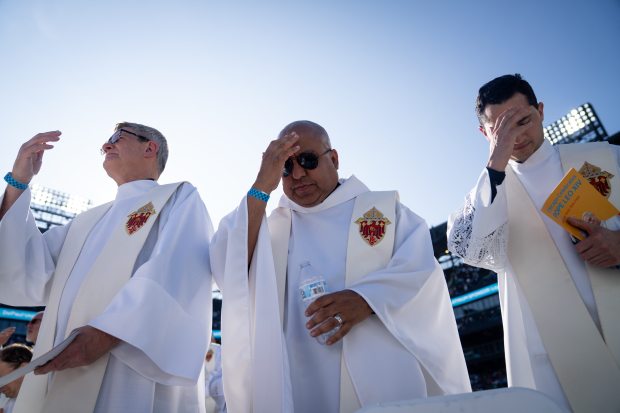 Father Ken Simpson, left, Father Walter Yepes and Father Robinson Ortiz make the sign of the cross at the end of a Catholic Mass while celebrating the election of Pope Leo XIV with a citywide gathering at Rate Field on June 14, 2025. (Audrey Richardson/Chicago Tribune)